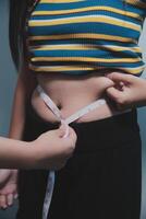 A woman measuring her waist with a tape measure photo