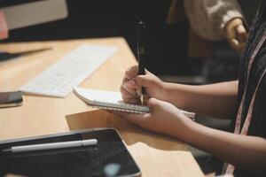 A person writing on a notebook with a pen photo