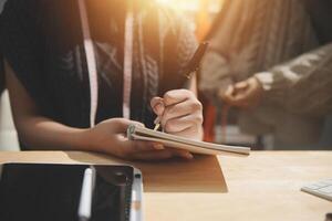 A person is writing in a notebook while sitting at a desk photo