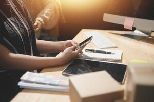 A person sitting at a desk with a cell phone and a laptop photo