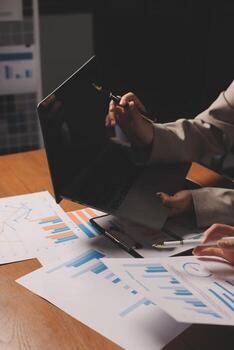 un persona es trabajando en un ordenador portátil con documentos y gráficos foto