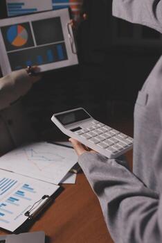 un persona es participación un calculadora y mirando a un papel con gráficos foto