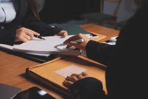 Two business people sitting at a table with papers and pens photo