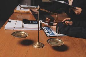 A lawyer and a judge are sitting at a table with a scale and a pen photo