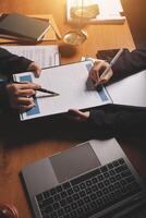 Two people sitting at a desk with a laptop and papers photo