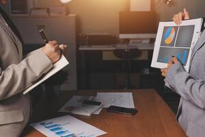 Two business people are looking at graphs on a tablet photo