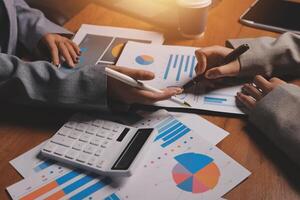 Business people working on a table with papers and calculators photo