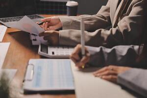 Two people sitting at a table with papers and a laptop photo