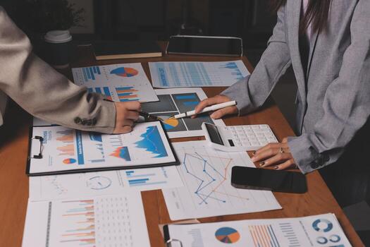 dos personas trabajando en un mesa con documentos y gráficos foto