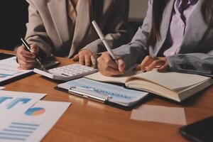Two business people sitting at a table with papers and pens photo
