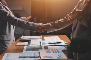 Two business people shaking hands over a table with papers photo