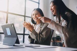 Two women are laughing and pointing at a laptop photo