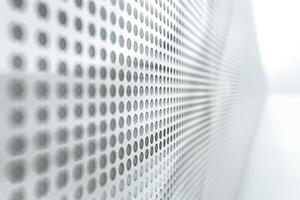 Abstract close-up of a textured wall with a series of perforated dots in shades of gray. photo