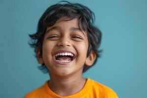 Cheerful young boy with curly hair laughing joyfully against a turquoise background. photo