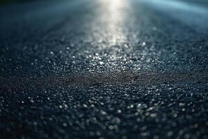 A close-up view of a wet asphalt road, glistening under soft light. photo
