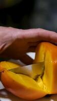 Cutting ripe fresh persimmon slices on a wooden board with a knife. Juicy, ripe persimmon being sliced, showcasing its vibrant orange color and smooth texture. video