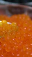 Red Caviar in a spoon background. Close-up of salmon fish roe caviar. Delicatessen. Texture of trout caviar backdrop. Shell shaped spoon full of red caviar. Seafood, rotating. video