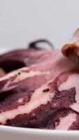 Cutting a large, freshly boiled octopus into a bowl to make a salad. video
