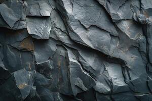 Textured surface of a dark gray slate rock showcasing intricate patterns and natural cracks. photo