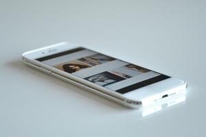 A sleek smartphone displaying a gallery of images on a white surface. photo