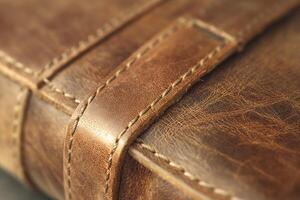 Close-up of a beautifully crafted brown leather notebook with intricate stitching and a textured surface. photo