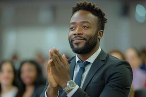 A focused Black man in a suit actively applauding during a formal event, showcasing engagement and positive energy. photo
