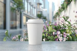 A blank white coffee cup stands on a stone surface, with a blurred cityscape and flowers in the background, evoking a serene morning vibe. photo
