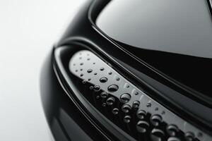 Close-up of a sleek, modern black car surface adorned with water droplets, showcasing its smooth curves and high-gloss finish. photo