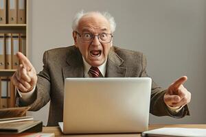 An elderly Caucasian man in a brown suit yells passionately while sitting at a desk with a laptop, surrounded by office supplies. photo