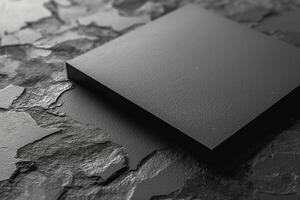 A sleek black square panel resting on a textured dark surface, creating a minimalist and modern aesthetic. photo