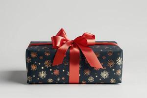 A beautifully wrapped black Christmas present adorned with a vibrant red bow and golden snowflake patterns. photo
