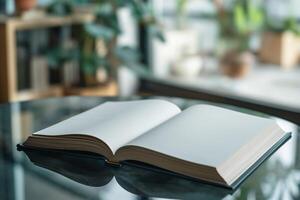 An open book with blank pages resting on a glass table, surrounded by soft greenery. photo