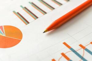 Close-up of colorful graphs and a vibrant orange pen, suggesting analysis and creativity in data presentation. photo