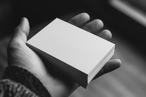 Close-up of a hand holding a stack of blank business cards in a monochromatic setting. photo