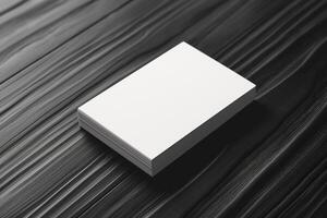 A stack of blank business cards on a textured black surface, ideal for branding possibilities. photo