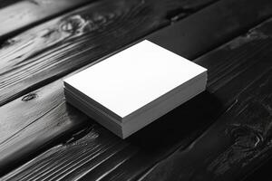 A stack of blank white cards resting on a dark wooden surface, creating a striking contrast. photo