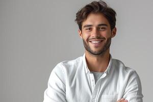 Young Caucasian man smiling confidently in a light-colored button-up shirt against a neutral background. photo