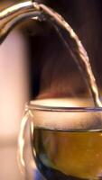 Making hot tea on the kitchen table. Boiling water is poured from the kettle into a cup with a tea bag. Transparent cup of freshly brewed tea on the kitchen table on a sunny day. video