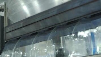 Close up view of a plastic bottle production line in a factory. Parts of transparent PET bottles move along an automated conveyor system. Showing modern PET drinking bottles manufacturing automation video