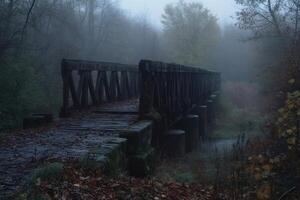 Old wooden bridge disappearing into the fog in a forest during a misty autumn morning photo