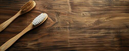 Two wooden toothbrushes rest on a rustic wooden surface photo