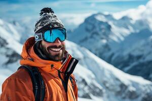 A man in an orange jacket and ski goggles smiles photo
