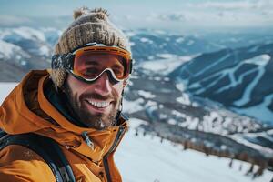 A man in a ski jacket and goggles smiles while standing on a snowy mountain photo