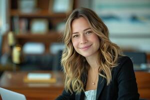 A woman in a business suit sitting at a desk with a laptop photo
