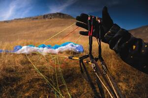 Paraglider untangles the lines of a kite before takeoff on a sunny day. Checking the sports equipment after landing on the ground photo