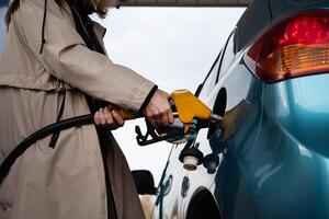 Pumping gas at the gas pump. The woman refuels the ca On a sunny day. A woman at a gas station. A woman refuels a car with gasoline at a gas station photo