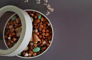 On a light background there is a round box filled On a sunny daywith various nuts and dried fruits. Mothers Day. Valentine's Day. International Women's Day.A delightful gift. Low-fat food. photo