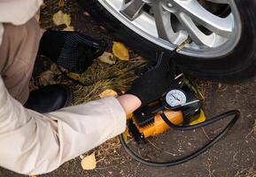 man driver hand inflating tires of vehicle, removing tire On a sunny day valve nitrogen cap for checking air pressure and filling air on car wheel at gas station. self service, maintenance and safety photo