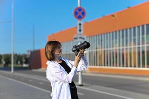 Beautiful woman taking picture outdoors with a analog camera photo