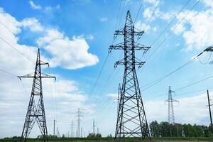 High voltage power lines leading through a green field. On a sunny day Transmission of electricity by means of supports through agricultural areas. photo